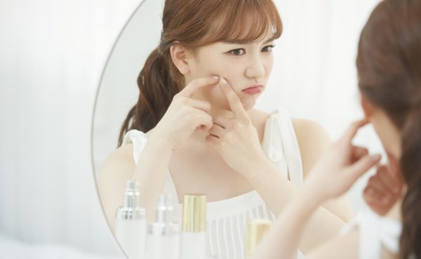 鏡越しに肌の調子を確認する女性